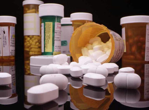 Assorted prescription pill bottles and tablets scattered.