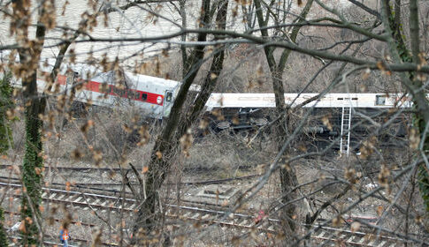 Train derailed in forested area, view through trees.