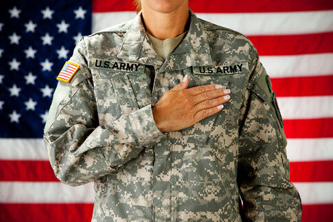 Soldier saluting in front of an American flag.
