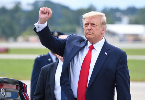 A political figure raising a fist in a gesture of confidence during an outdoor event